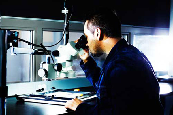 male looking through microscope - forensics