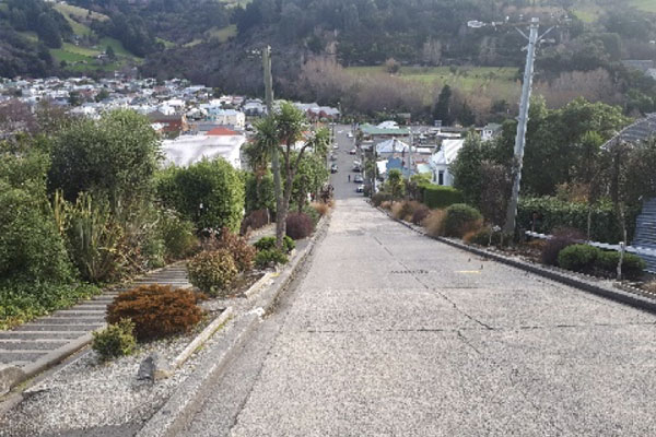 Photo looking down a steep road toward a town with a mountain in the background