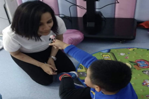 Vriti Bajaj sitting with a child who is offering her a sucker