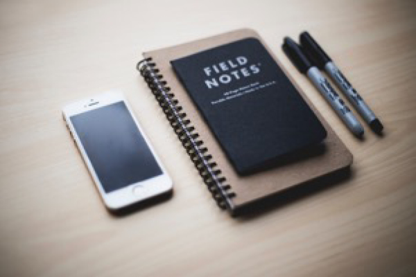 mobile phone, field notes notebook and two markers on a table