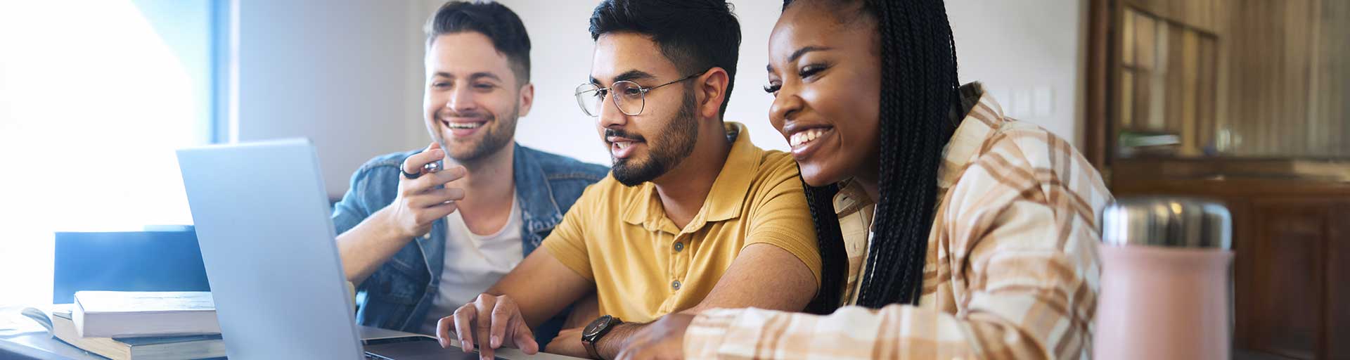 3 people sitting around a laptop