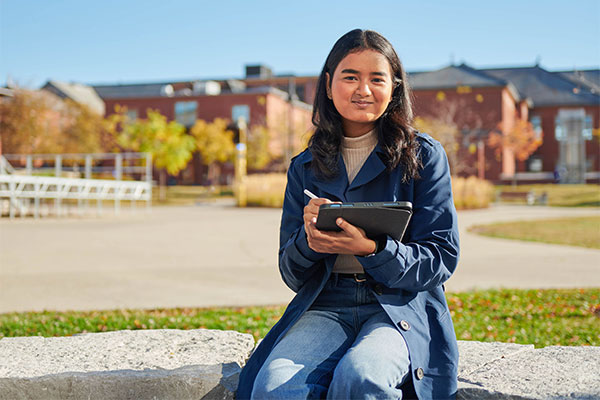 person sitting outside holding a tablet and smiling