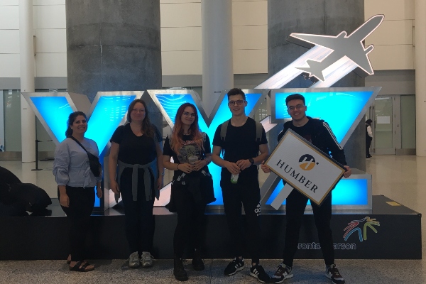 Humber students standing in front of YYZ signage