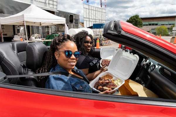 Happy customers in their car showing the ribs they purchased