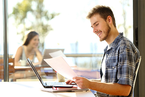 Caucasian male student happily reading a letter 
