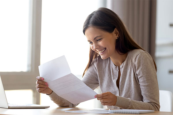 Young female student smiling and opening a letter