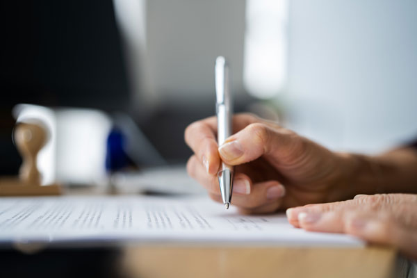 Close up shot of someone holding a pen writing on paper