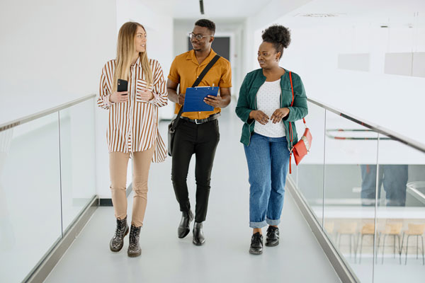 Two diverse student interns with their female manager walking in a hallway