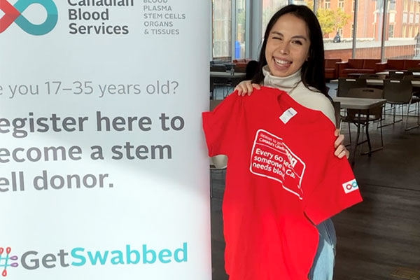 Student holding up a Canadian blood services t-shirt