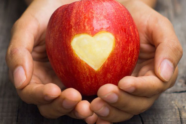 Hands holding an apple with a heart in it