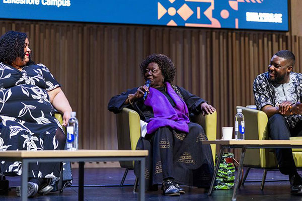 three people sitting on stage for a discussion panel