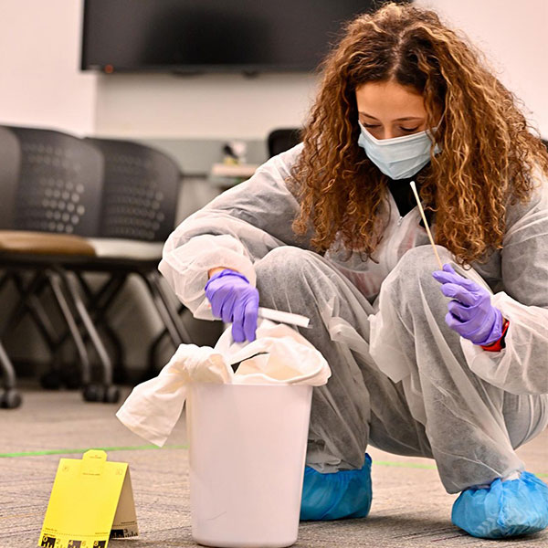 student examining garbage can for DNA