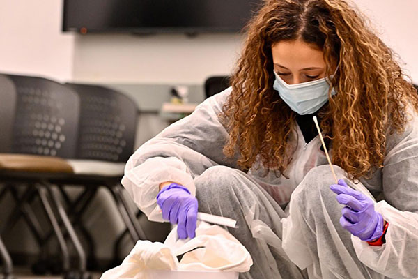student examining garbage can for DNA