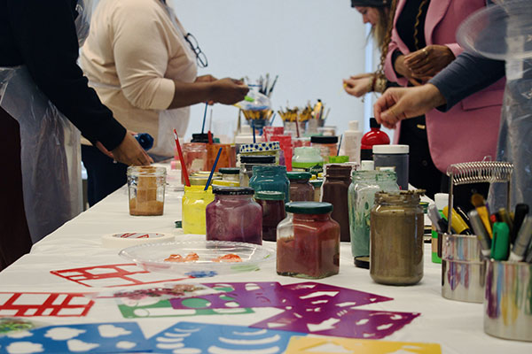 people standing around a table that has jars of paint