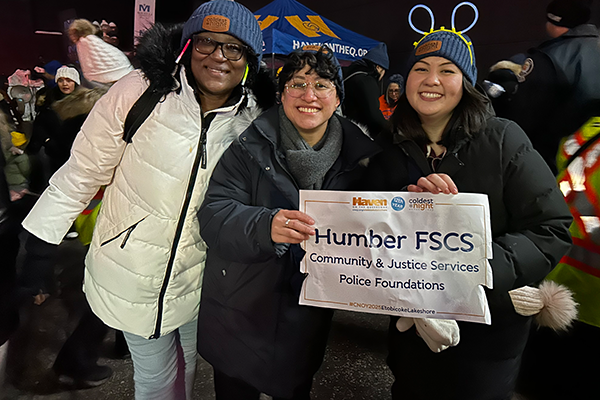 students  smiling and holding a sign that reads "Humber FSCS Community & Justice Services Police Foundations"