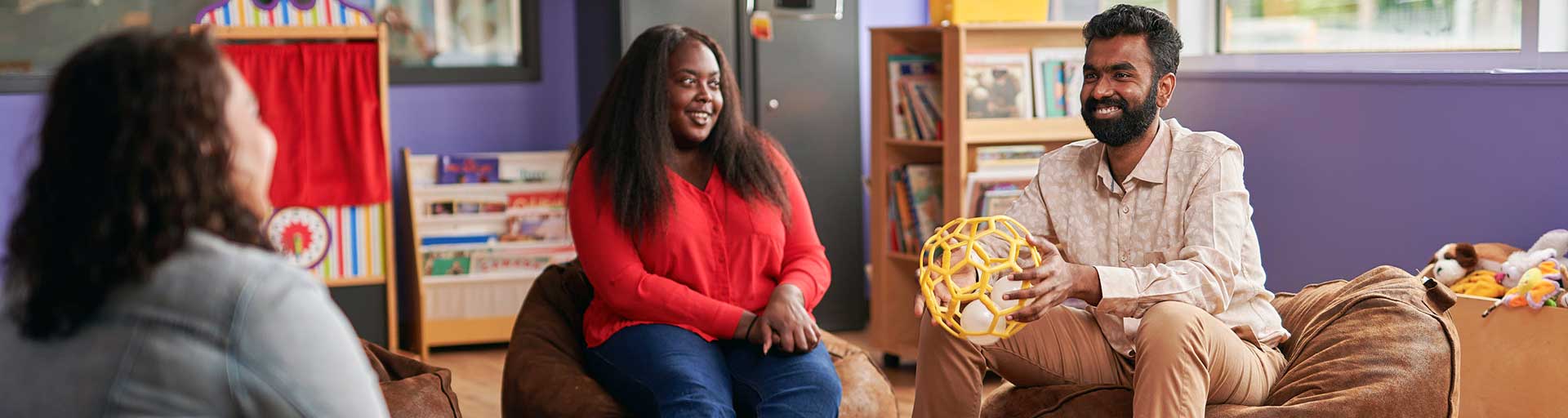 three students sitting on bean bag chairs smiling