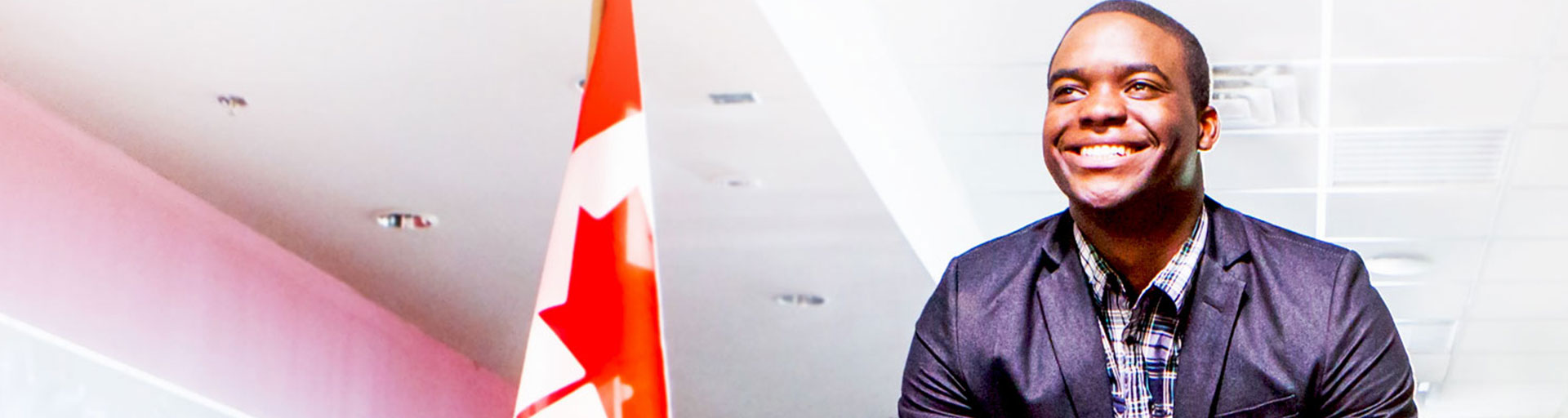 man smiling standing near a Canadian flag
