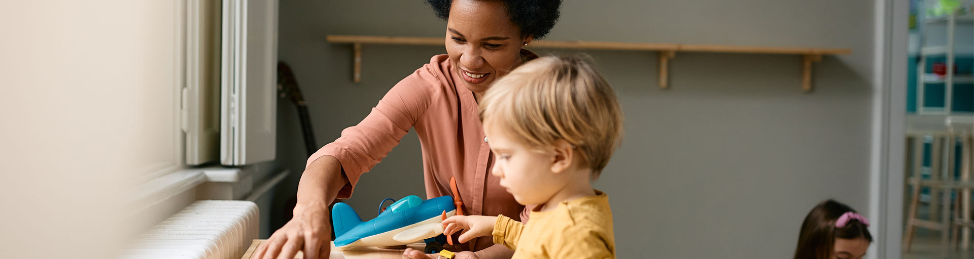 Small child and teacher using puzzles while playing at preschool