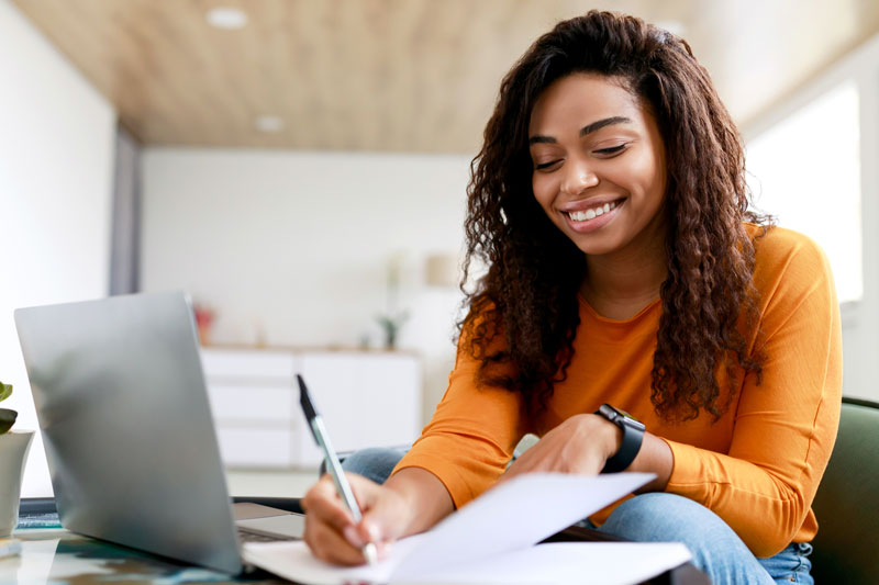 Student studying at home with laptop and notebook